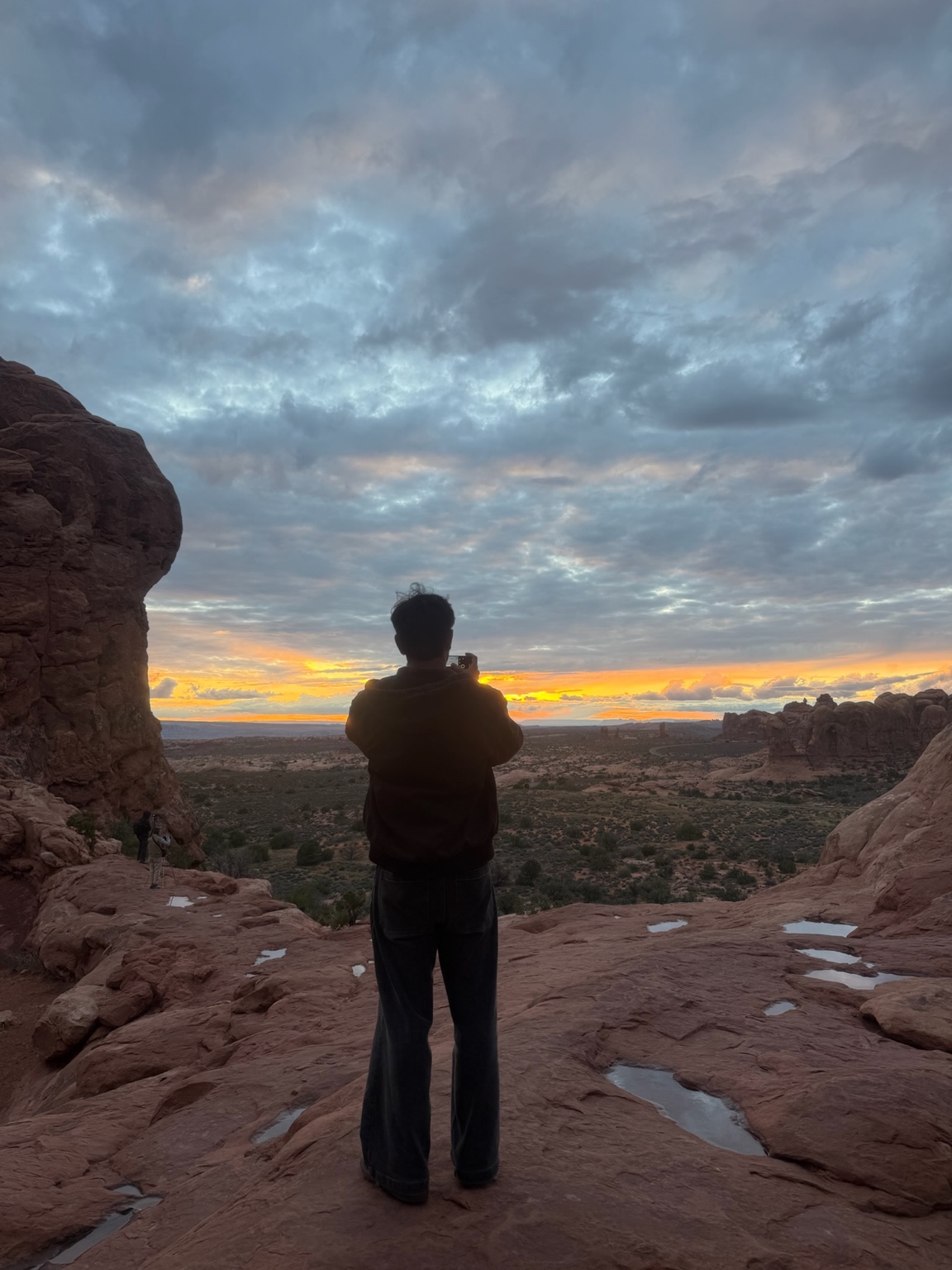 A person taking in a sunset among rock formations