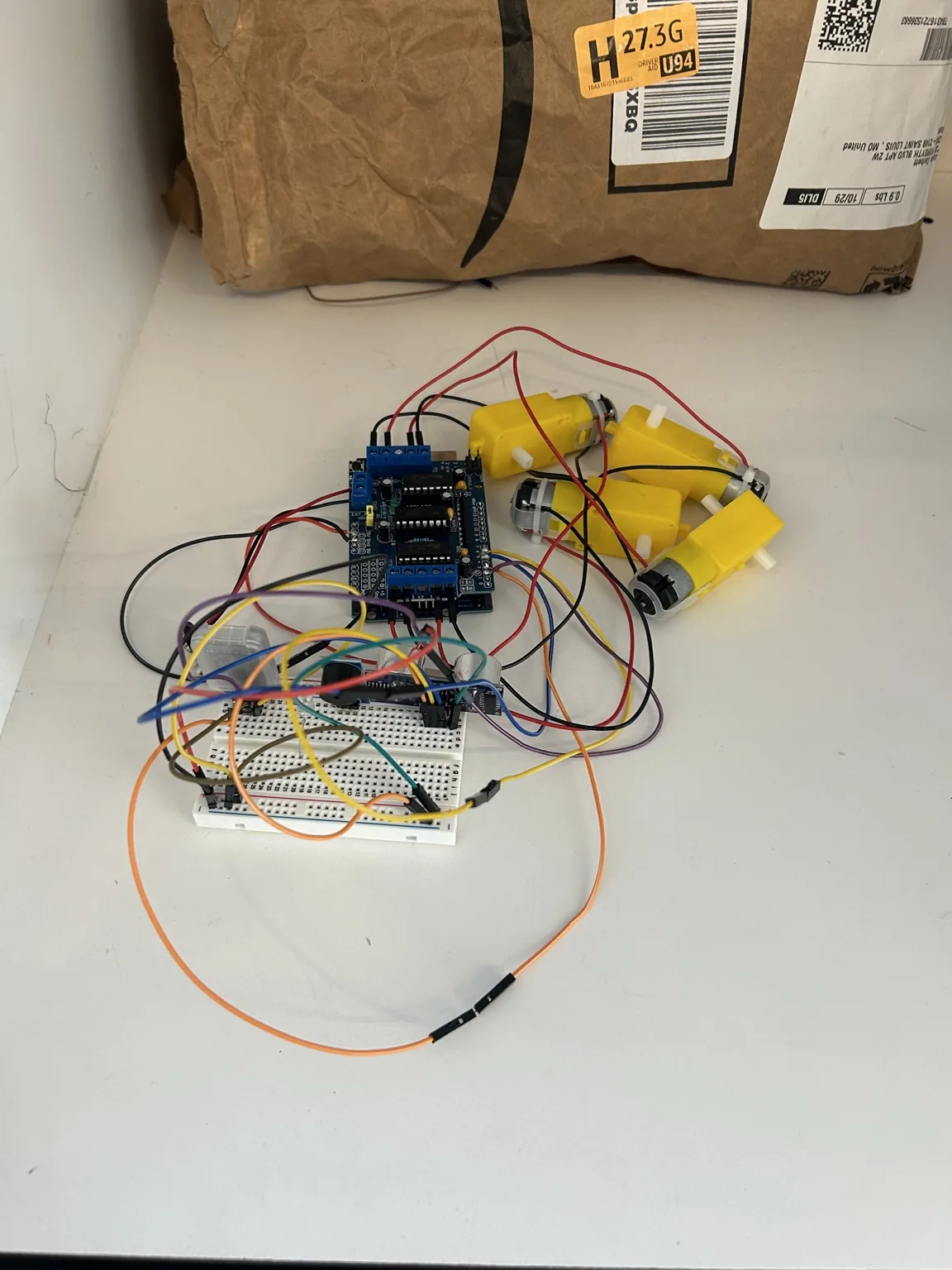 Breadboard prototype connected to a motor-control board and four yellow geared motors