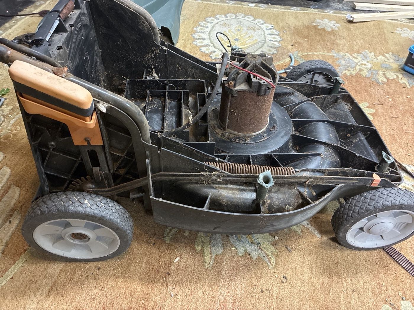 Side view of my partially disassembled mower showing the exposed motor, chassis, and wheels